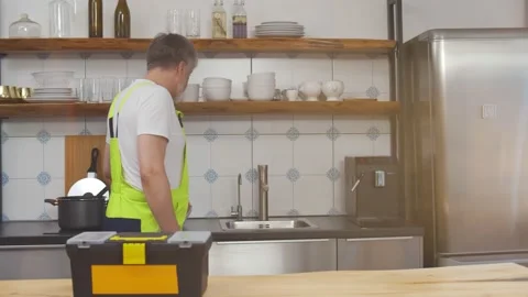 Senior plumber waking in kitchen putting toolbox on counter top and examining Stock Footage 143976363