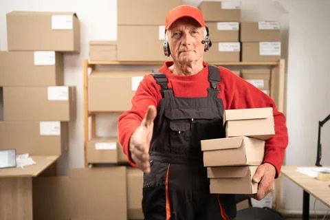 Senior postal worker holding parcels in post office looking at camera Stock Photos