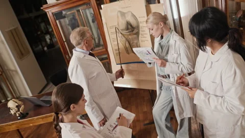 Senior Professor Explaining Knee Anatomy to Diverse Medical Students Stock Footage 341650543
