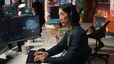 Senior programmer in AI startup office putting on headphones Stock Photos