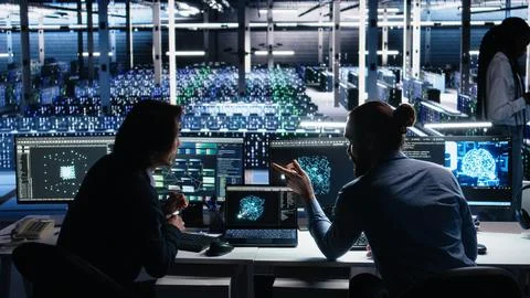 Senior programmer and coworker in data center coding with generative AI Stock Photos