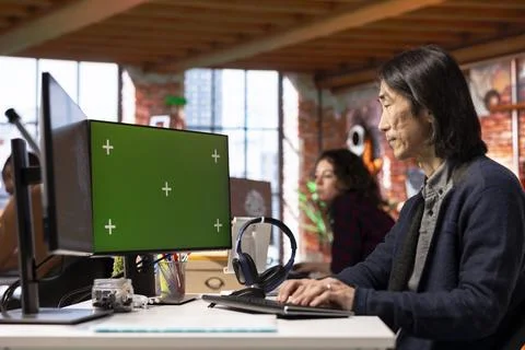 Senior programmer using green screen PC in AI tech startup Stock Photos