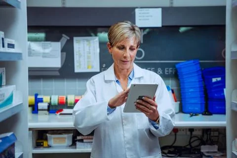 Senior qualified pharmacist scrolling through to-do list on digital tablet Stock Photos