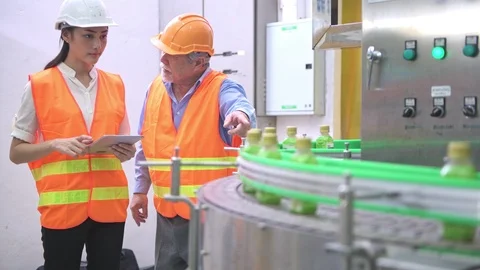 Senior quality inspector teaching junior team member in factory. Video stock 92400023