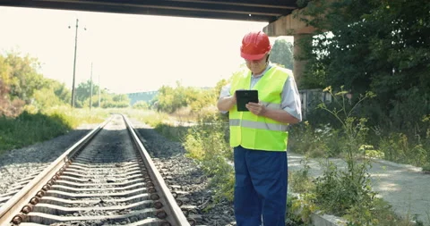 Senior railroader in uniform using tablet when checking serviceability of rails Stock Footage 135568880