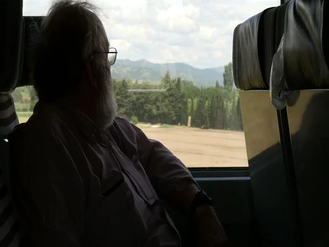 Senior retired man on train looking out window while on vacation Stock Footage