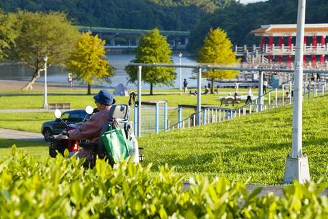 Senior Riding Electric Mobility Scooter Along Path at Dahu Park Neihu Taipei Photos