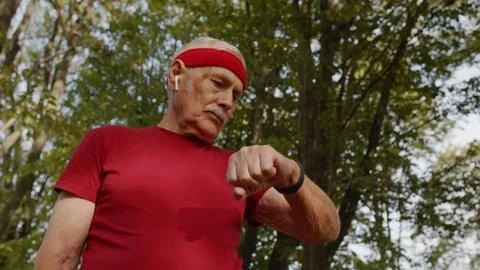 Senior runner man in park using smart watch, tracking distance, checking pulse Stock Photos