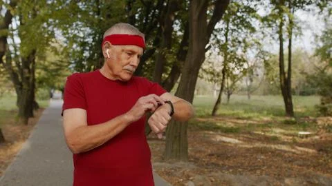 Senior runner man in park using smart watch, tracking distance, checking pulse Stock Photos