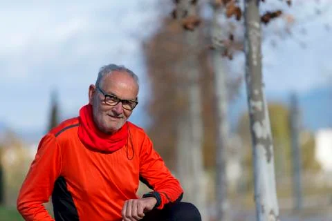 Senior runner man resting at the park while monitoring his exercise Stock Photos