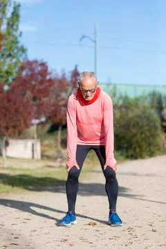 Senior runner resting outside in sunny autumn nature. Stock Photos