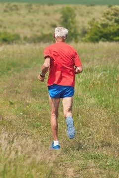 Senior runner running on the meadow at springtime Stock Photos
