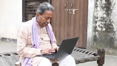 Senior rural indian man using laptop at home Check government scheme online.. Vídeos de archivo 329090799