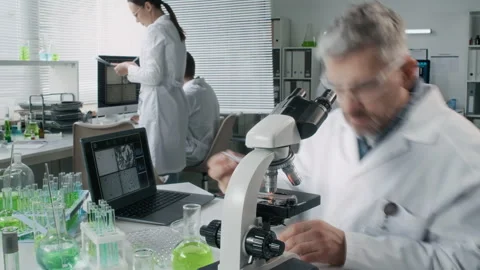 Senior Scientist Analyzing Samples Looking in Microscope Timelapse Stock Footage 330676914