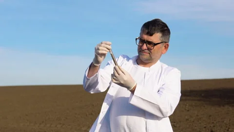 Senior scientist studying sample of soil in field. Soil sampling for chemical Stock Footage 240746410