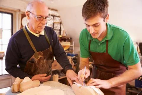 Senior shoemaker training apprentice to make shoe lasts Stock Photos