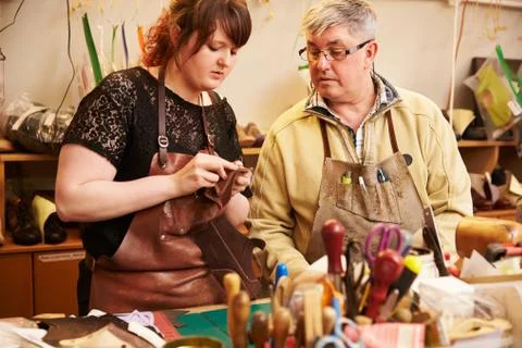 Senior shoemaker training apprentice to work with leather 库存照片