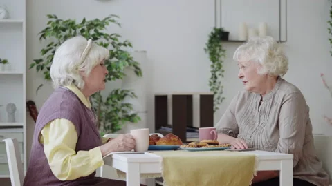Senior sisters discussing life problems and drinking tea in the kitchen, support Stock Footage 225691062