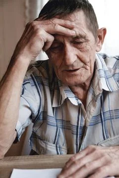 Senior sitting at the table and thinking about something or forg Stock Photos