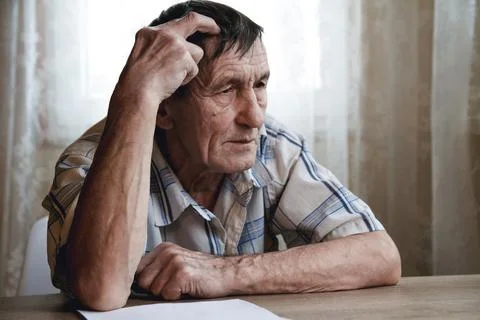 Senior sitting at the table and thinking about something or forg Stock Photos