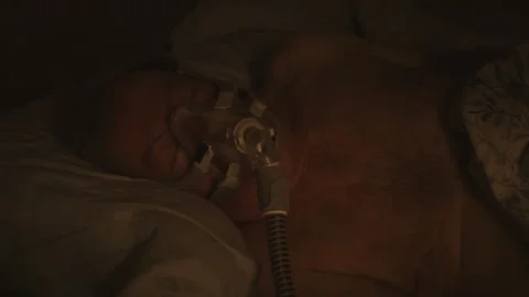Senior sleeping on his side with CPAP sleep breathing therapy forced air mask on Stock Footage 327389744