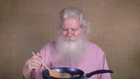 Senior smiling man is roasting coffee green beans on frying pan. Stock Footage 119876080