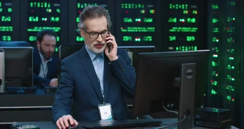 Senior specialist programmer in glasses and jacket sits at workplace at computer Video stock 145298355