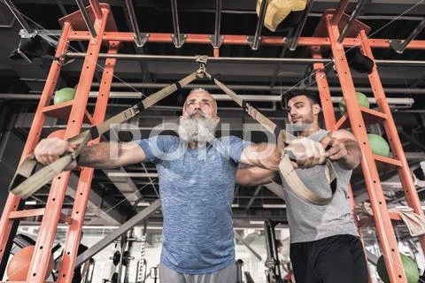Senior sportsman with instructor are training in athletic center Stock Photos