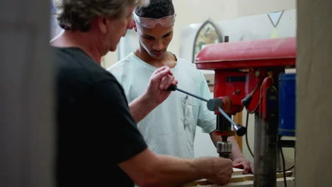 Senior staff guiding carpentry apprentice to use machine at workshop. Candi.. Stock Footage 246976300
