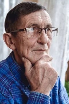 Senior standing at the window and thinking about something or fo Stock Photos