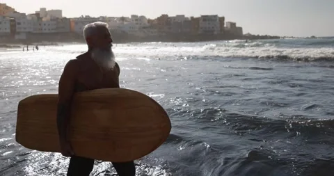 Senior surfer man walking on the beach with surfboard Stock Footage 151685683