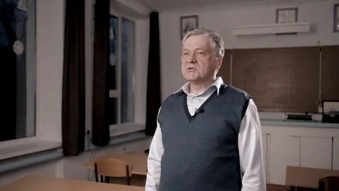 Senior teacher talking into camera as if being interviewed Stock Footage 102847668