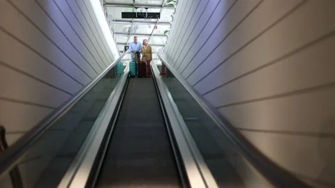 Senior tourists couple going down on airport escalator Stock Footage 300857942