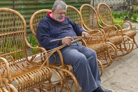 Senior Ukrainian man sorting withe while making whicker rocking chair Stock Photos