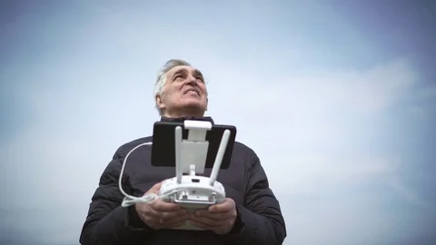 Senior uses drone controller at sky background. 4K Stock Footage 74970726