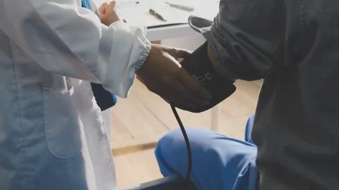 Senior using a blood pressure cuff during a telemedicine consultation via d.. Stock Footage 343707887