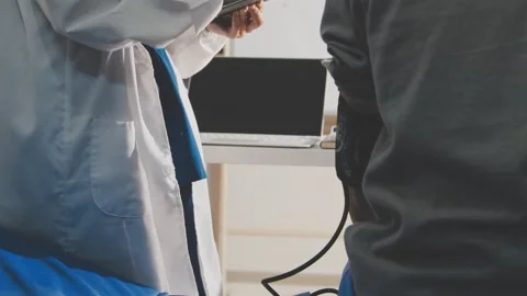 Senior using a blood pressure cuff during a telemedicine consultation via d.. Stock Footage 343707910