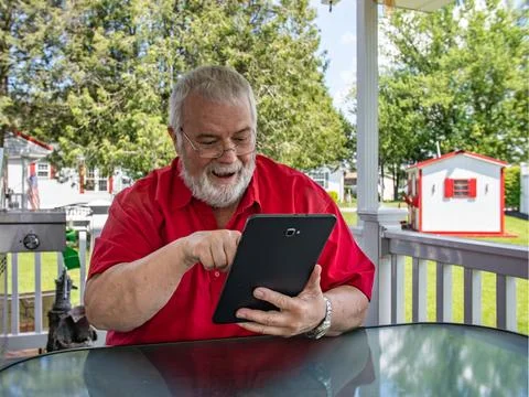 Senior Using Tablet on Porch While Enjoying Warm Weather and Greenery in Ba.. Stock Photos