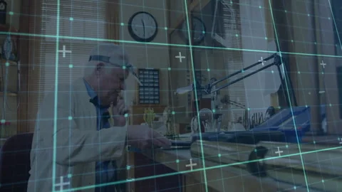 Senior watchmaker using loupe examining components at bench showing glowing Stock Footage 307463222