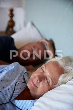 Senior white couple asleep in their bed, waist up, close up, vertical Stock Photos