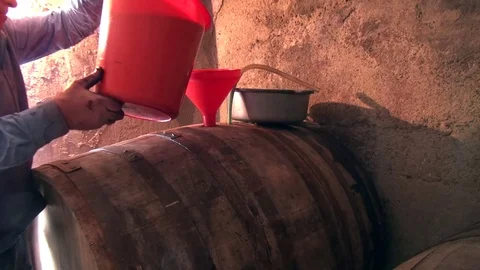 Senior winemaker pouring wine in a barrel in a wine cellar Stock Footage 69782329