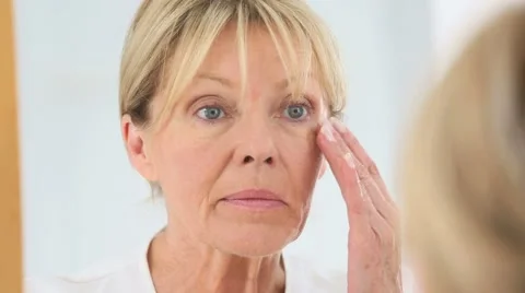 Senior woman applying cosmetic lotion on her face Stock Footage