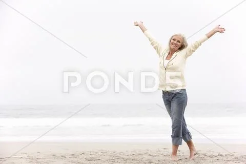 Senior Woman With Arms Outstretched On Winter Beach Stock Photos