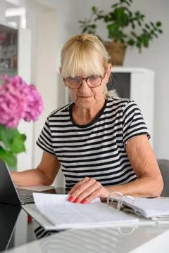 Senior woman checking documents while writing notes Stock Photos