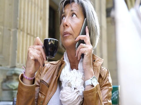 Senior woman at coffee shop terrace talking on phone Stock Footage