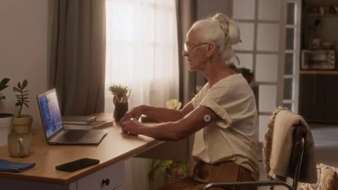 Senior Woman with Diabetes Patch Having Telemedicine Consultation on Laptop Vídeos de archivo 320972782