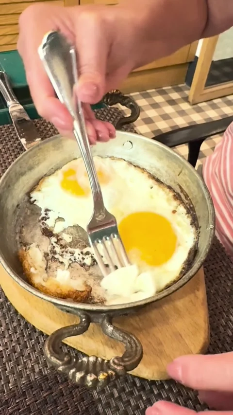 Senior woman eating the fresh made fried eggs from metal vintage pan Stock Footage 287002853