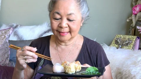 Senior woman is enjoying eating Dim Sum Chinese food Stock Footage