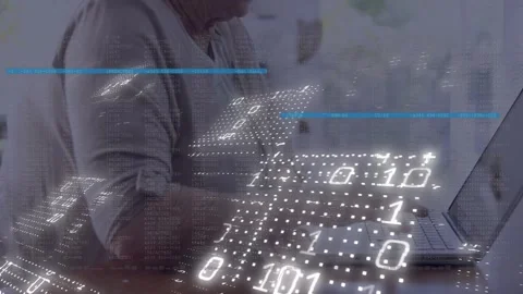 Senior woman entering data at table, right hand starting typing as binary grid Stock Footage 329611151
