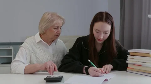 Senior woman explaining math on calculator to teen girl Stock Footage 317079253